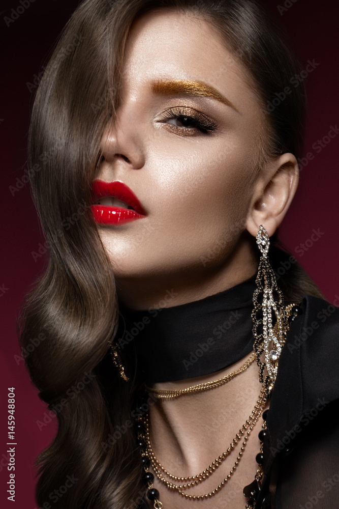 Beautiful girl with red lips and golden eyebrows, curls in Hollywood style. Beauty face. Photo taken in the studio.