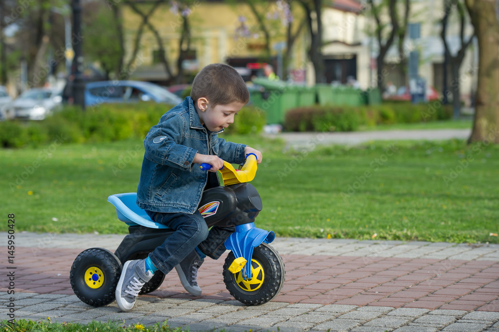little boy ride toy motorcycle on sidewalk little boy ride toy motorcycle on sidewalk