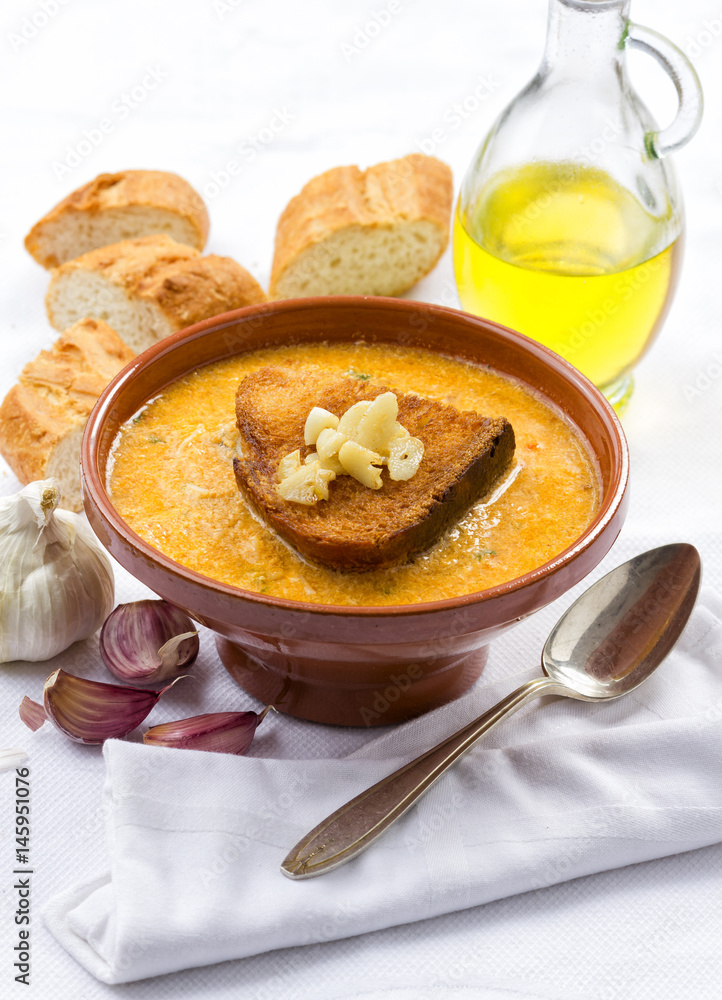 A bowl of traditional garlic soup topped with fried bread. A bowl of traditional garlic soup topped with fried bread.