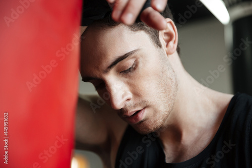 Portrait of tired boxer near punching bag