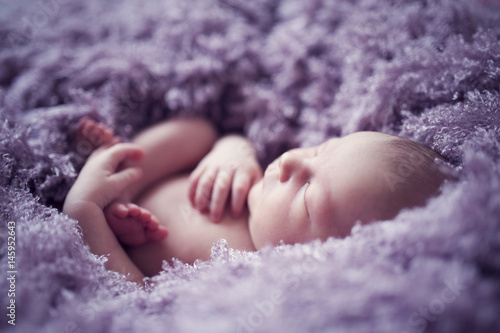 Sleeping baby in violet fur blanket