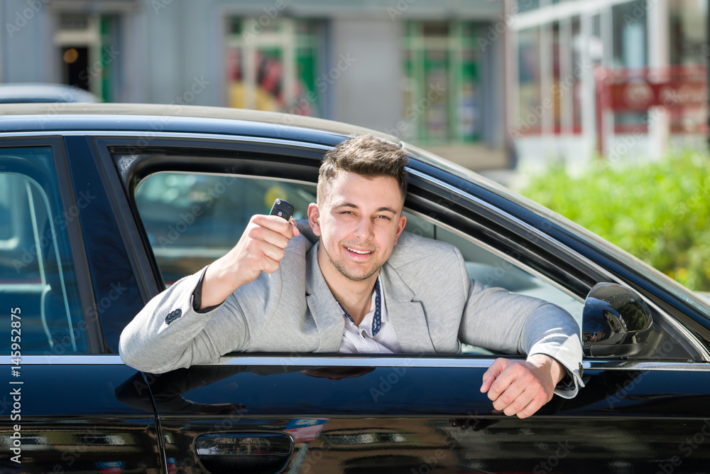 young owner man looking out from car window and holding a car alarm key