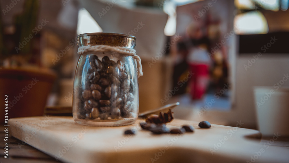 Roasted coffee beans in glass jars closed with a wooden lid.
