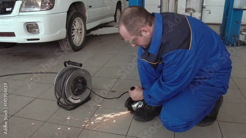 car mechanic work with circular saw cutting metal with sparks in super slow motion 120 fps photo