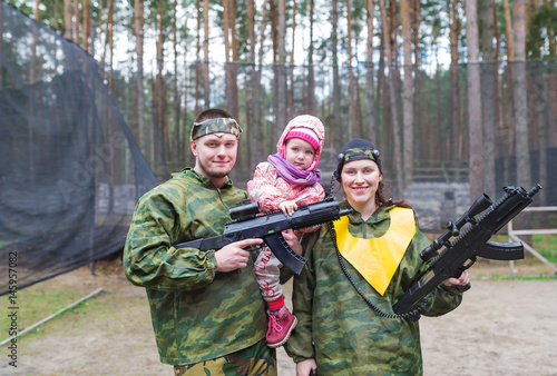Obraz na płótnie Portrait of family of three. Game in laser tag in the summer wood. w salonie