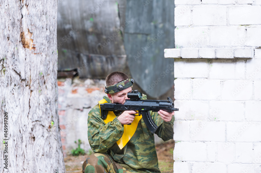 Fototapeta premium Man playing paintball in overalls with a gun