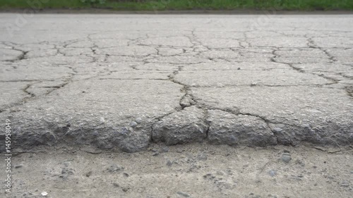 Cracked and broken asphalt road. Bad road conditions. Dolly shot.