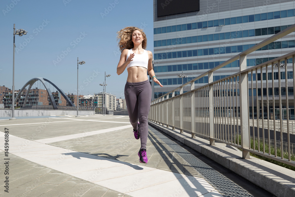 fit woman running in urban environment in summer