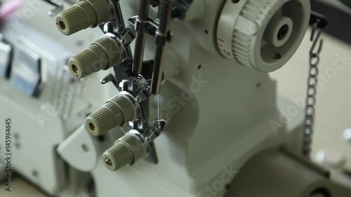 Closeup of details of professional sewing machine in factory interior. Real time full hd video footage. photo