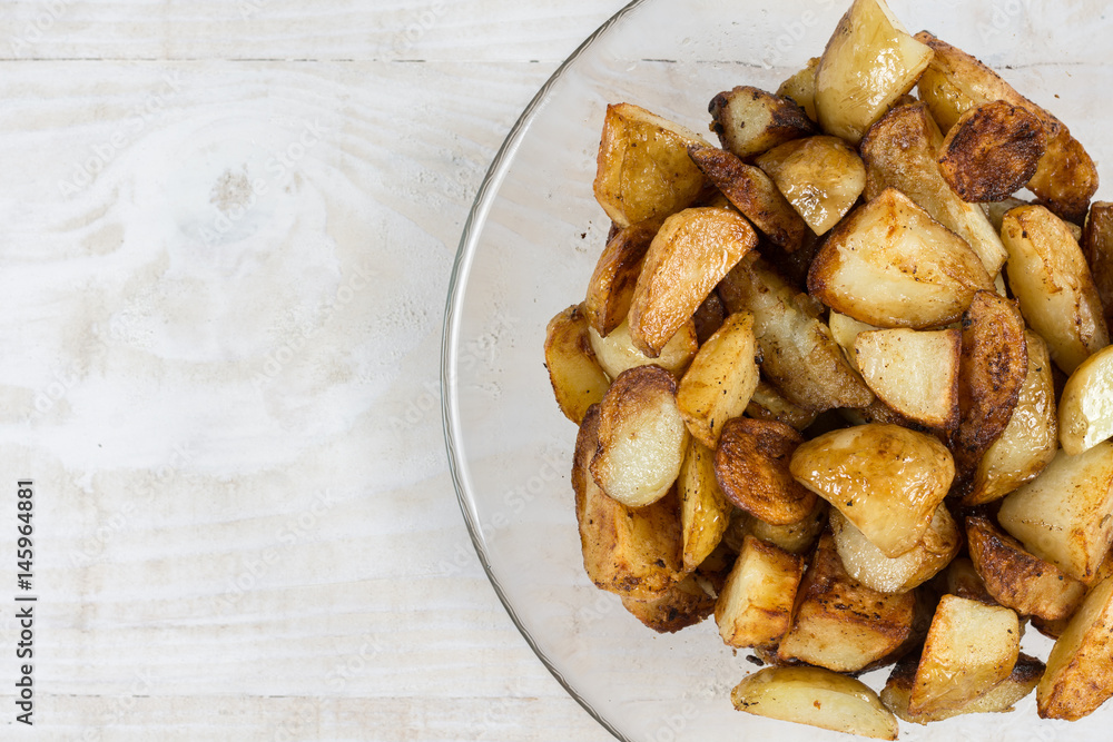 Fried young potatoes in the bowl above wooden background Fried young potatoes in the bowl above wooden background