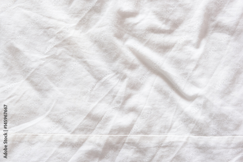 Top view of wrinkles on an untidy white bed sheet in a bedroom after a long night sleep and waking up in the morning. Abstract texture background. Top view of wrinkles on an untidy white bed sheet in a bedroom after a long night sleep and waking up in the morning. Abstract texture background.