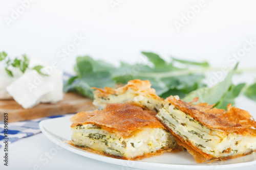 Homemade cheese and spinach pie on a white plate. Shallow depth of field.