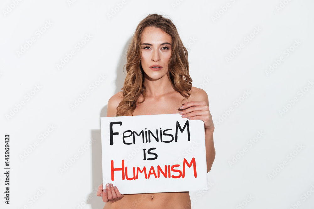 Serious woman feminist holding nameplete near breast Serious woman feminist holding nameplete near breast