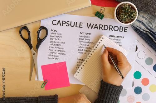 Woman creating a capsule wardrobe: fashion, minimalist and technology concept. Flat lay