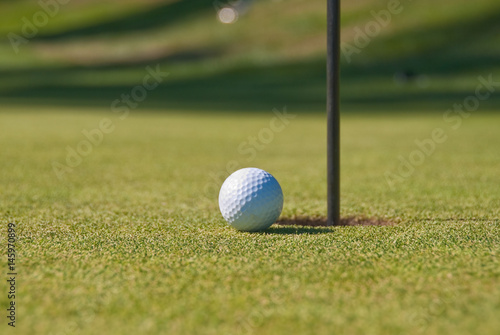Golf ball on green with flag.