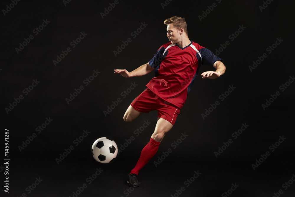 Professional Soccer Player Shooting At Goal In Studio