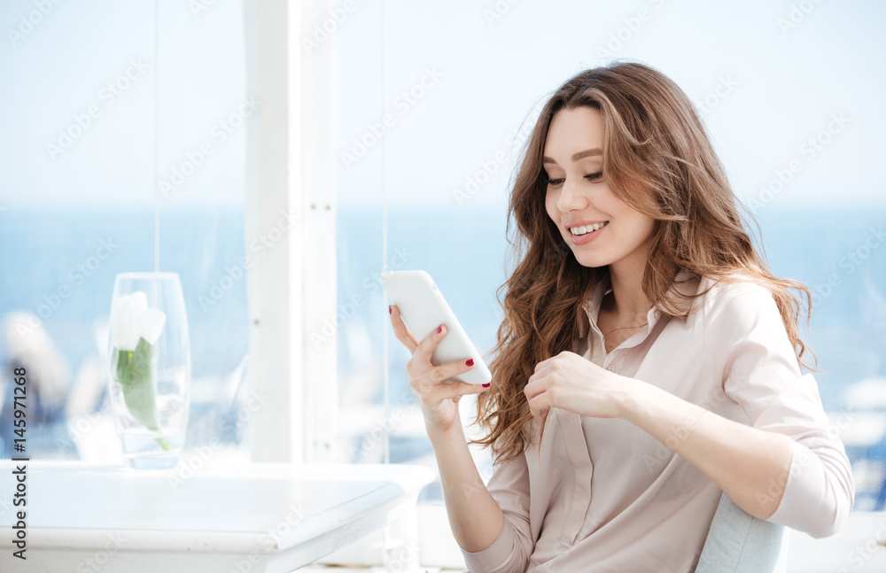 Young smiling woman using smartphone in cafe Young smiling woman using smartphone in cafe
