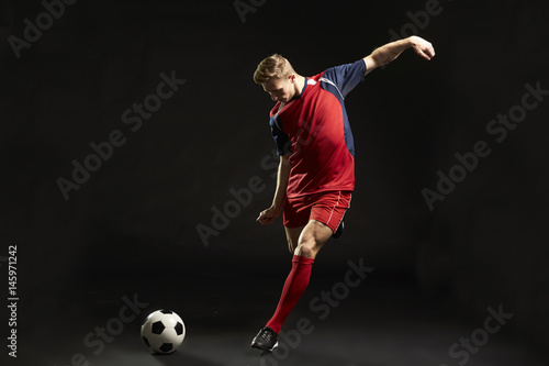 Fototapeta Professional Soccer Player Shooting At Goal In Studio