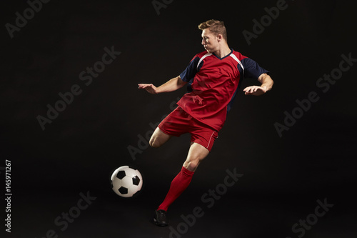 Fotografie, Tablou Professional Soccer Player Shooting At Goal In Studio