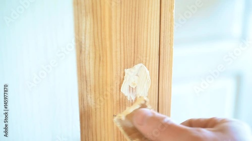 Close-up of hand spackling a round countersunk hole with screw head in door frame by filling the hollow cavity in wood with putty