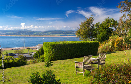 Bench or chairs with a table on the lawn with a magnificent view of the fusion of the Exe River with the English Channel (La Manche). City of Exmouth. Devon. UK