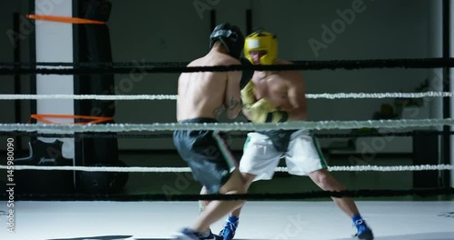 Professional sparring of two (young) partners of boxers in the ring, practice strike technique, rack, defense and endurance, in protective helmets. Concept: love sports, young boxers, love to win.