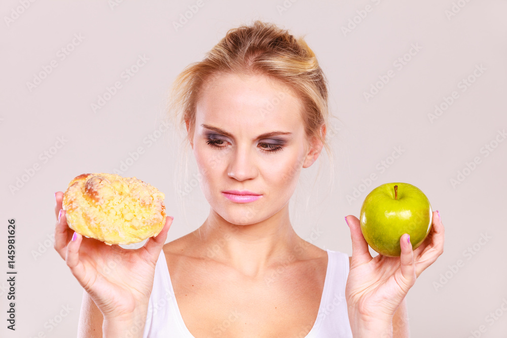 Woman holds cake and fruit in hand choosing Woman holds cake and fruit in hand choosing
