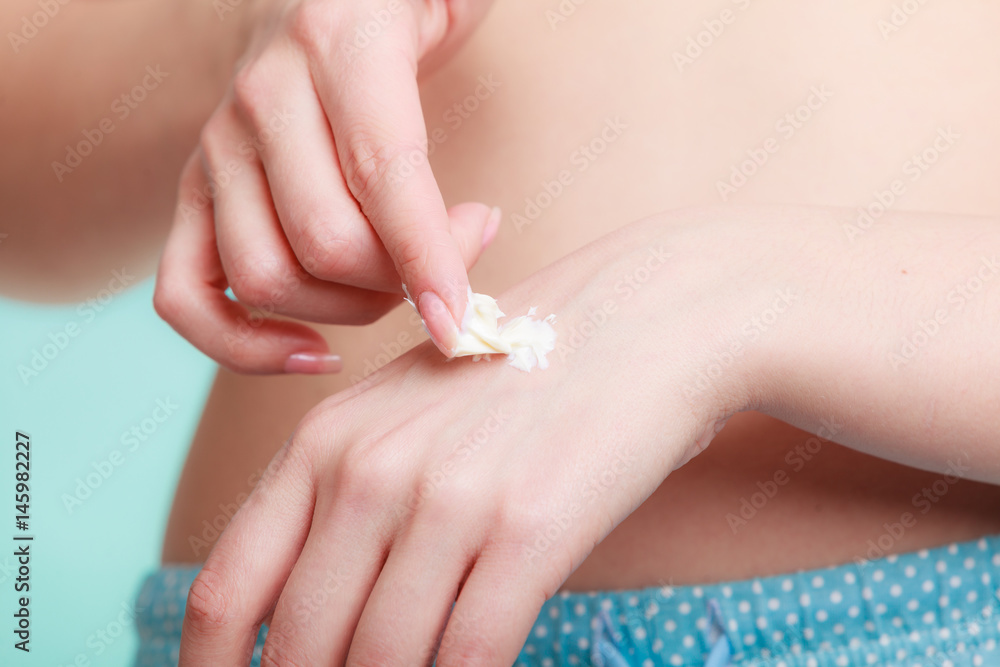Naklejka premium Woman putting white cream on hand
