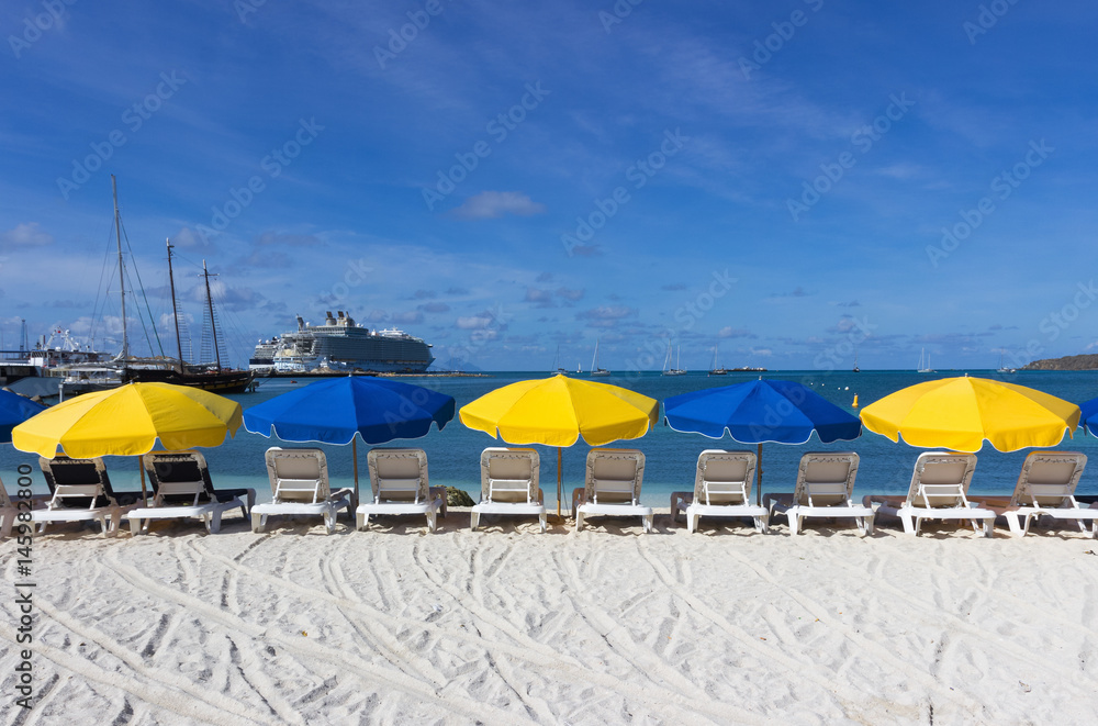  beach chairs and  colorful umbrellas on caribbean island st.Marten