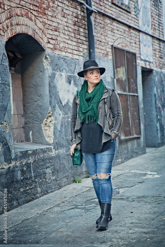 Fashionable 30-something woman walking in urban alley