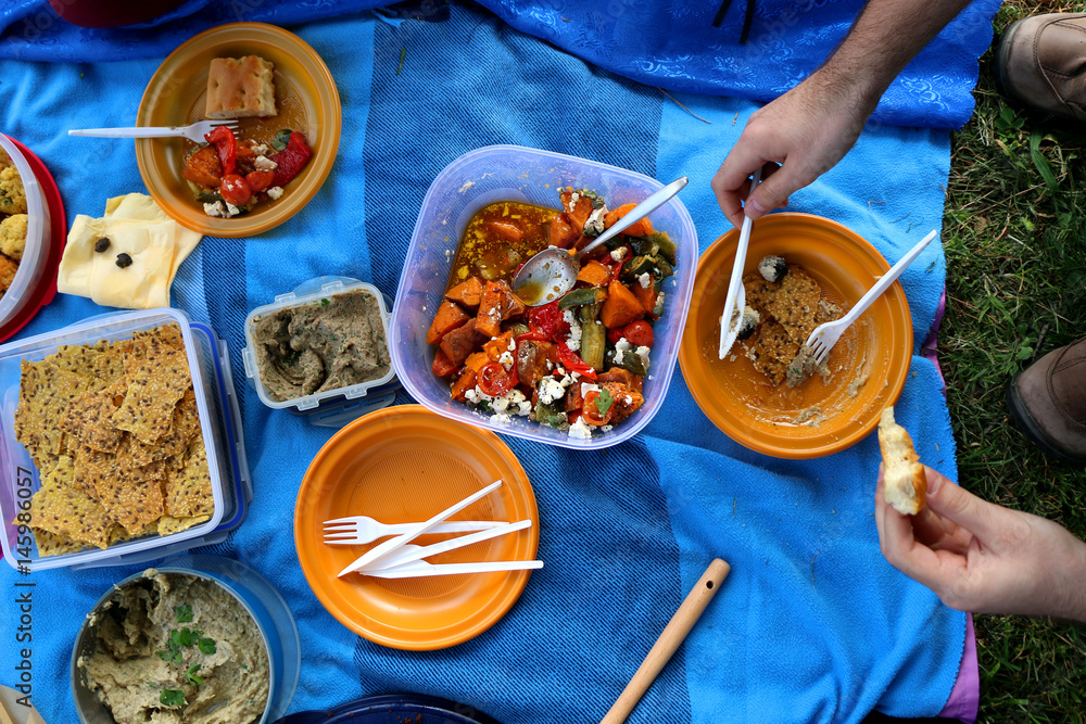 Unrecognizable person eating various picnic food: roasted vegetables