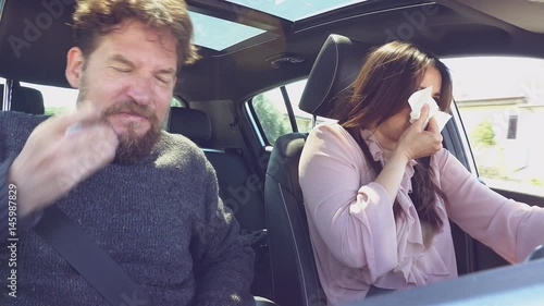 Couple driving car sneezing with strong allergy for spring with pollen in car