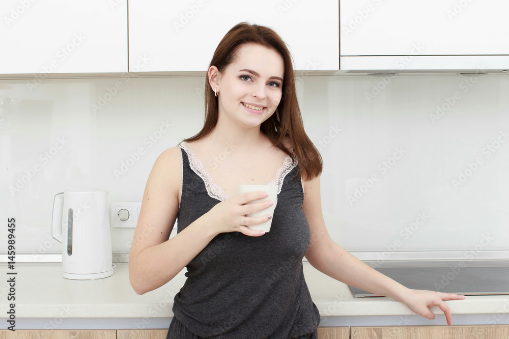 young woman With black hairdrinking coffee in the kitchen young woman With black hairdrinking coffee in the kitchen