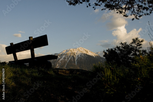 Panorama  Snowy mountains photographed in spring during sunset  in the foreground a wooden bench  Alps  Switzerland