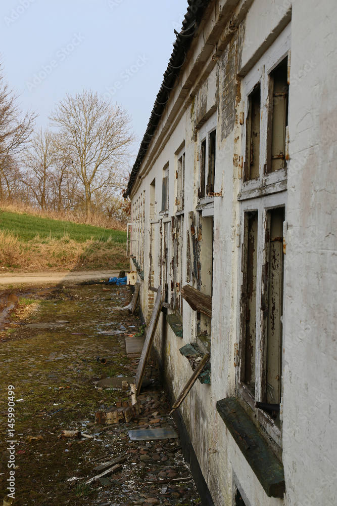 Fassade eines verlassenen Bauerhauses mit kaputten Fenstern