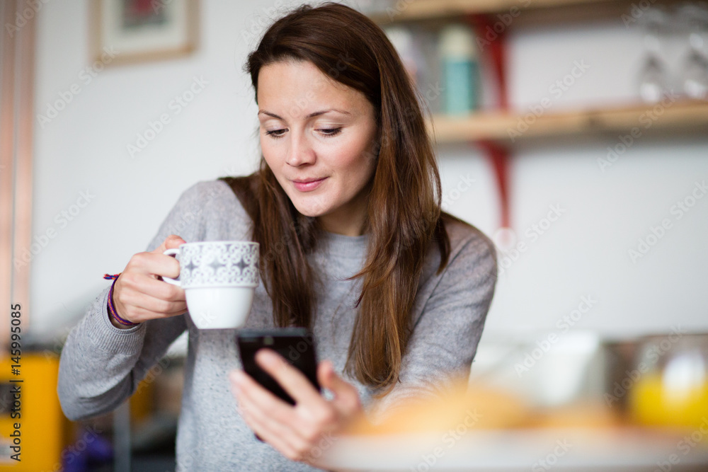 Young adult female having morning coffee and checking smartphone Young adult female having morning coffee and checking smartphone