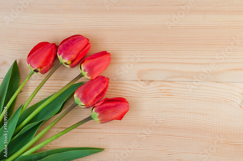 Fototapeta Naklejka Na Ścianę i Meble -  A beautiful bouquet of red tulips on a wooden background