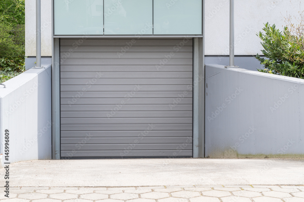 Graues Rolltor einer Tiefgarage mit Einfahrt Graues Rolltor einer Tiefgarage mit Einfahrt