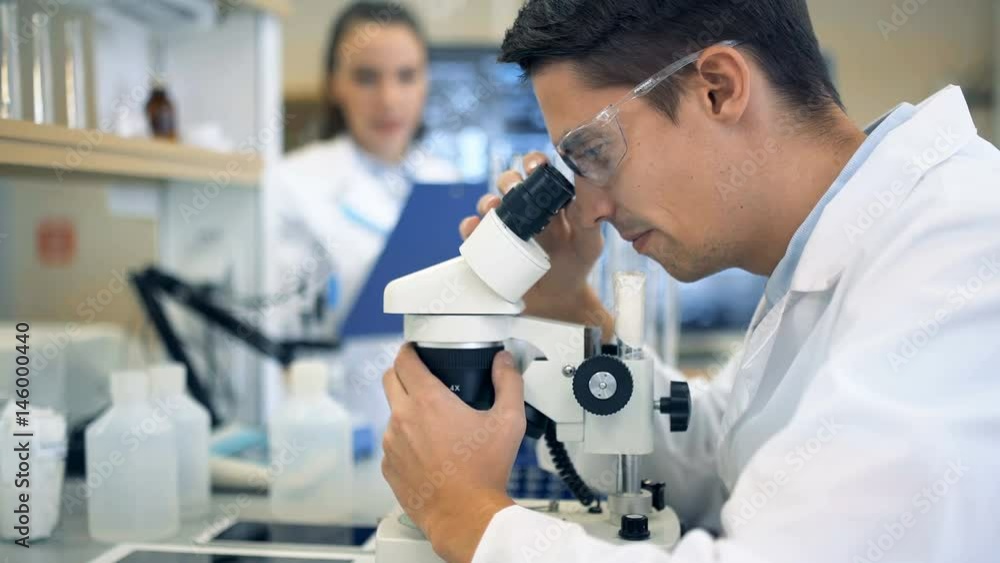 A male scientist working in a lab with microscope A male scientist working in a lab with microscope