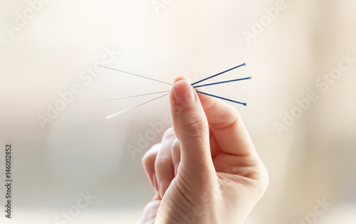 Foto Female hand with needles for acupuncture on blurred background