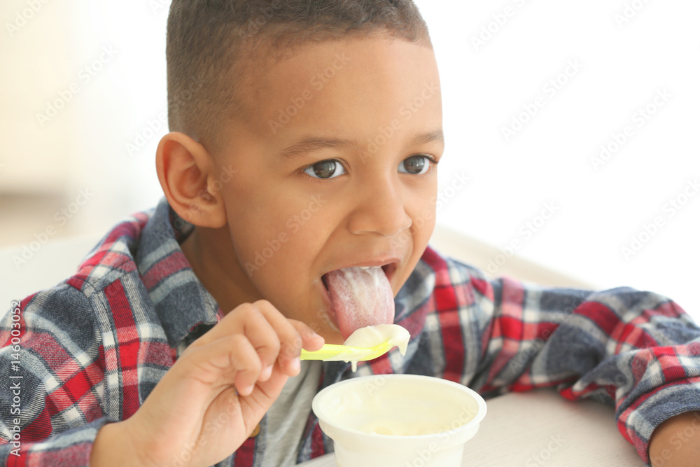 Cute African American boy eating yogurt at home, closeup Cute African American boy eating yogurt at home, closeup