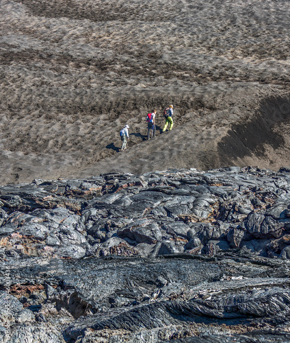 The active lava flow from a new crater on the slopes of volcanoes Tolbachik and group of tourists - Kamchatka, Russia photo