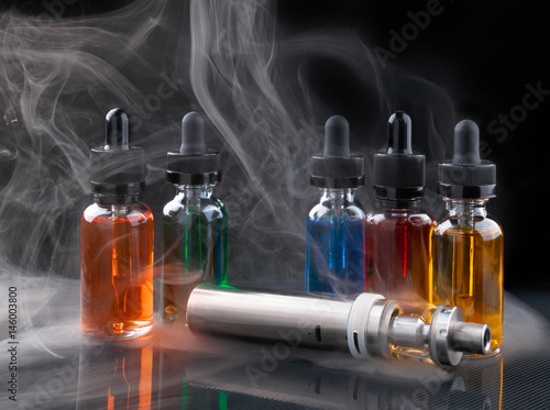 Electronic cigarette and vape liquids within vapor on black background