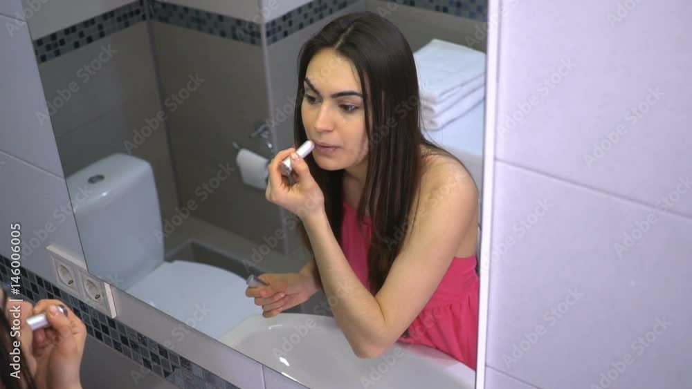 Girl paints lips and smiles happily of the makeup