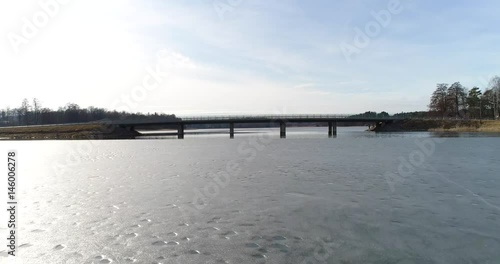 Lohjansaari bridge, Cinema 4k aerial flight under a bridge, at frozen lohjanjärvi, near lohjansaari island, on a sunny spring, in Lohja, Finland photo