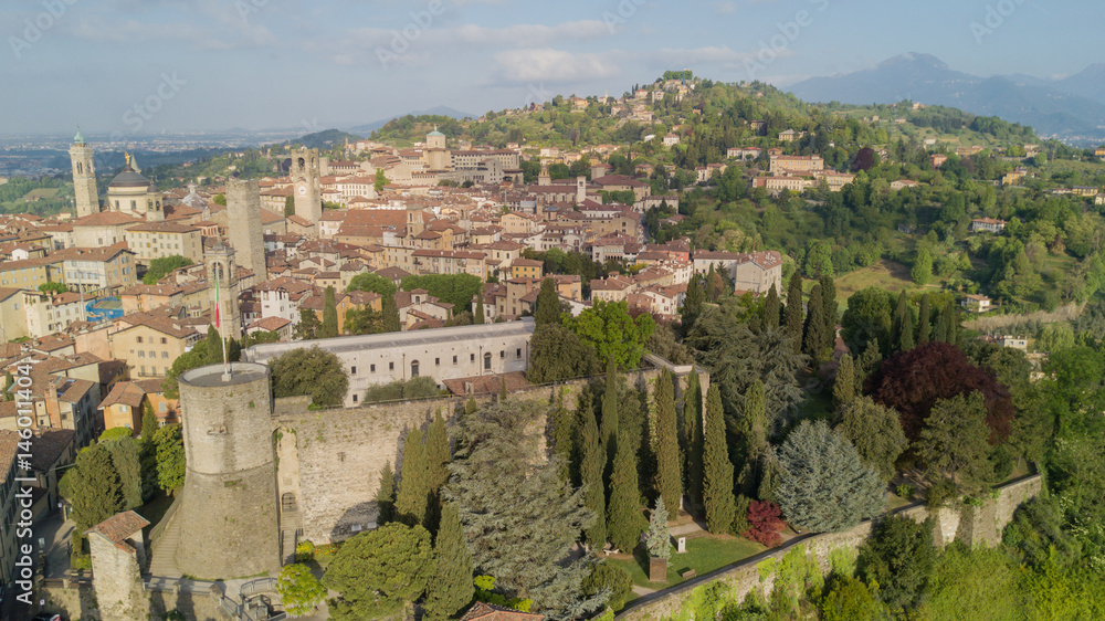 Drone aerial view of Bergamo - Old city (upper town), Italy. Landscape on the city center, the old fortress and its historical buildings during a wonderful blu day