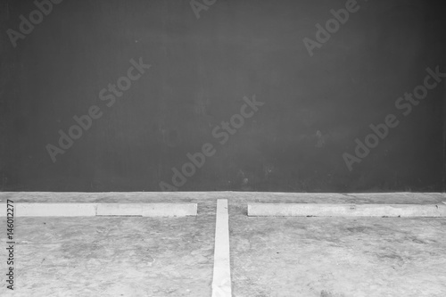 Closeup surface line slot for parking on cement floor with blurred dark gray cement wall in the garage textured background in black and white tone with copy space