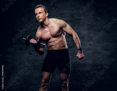 Portrait of shirtless athletic male doing a biceps workout with dumbbell. © Fxquadro