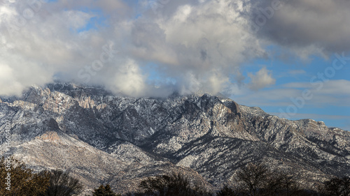 low clouds surrounding a mountain lightly covered in snow