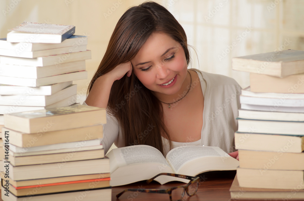 Portrait of clever student with open book reading in college library Portrait of clever student with open book reading in college library